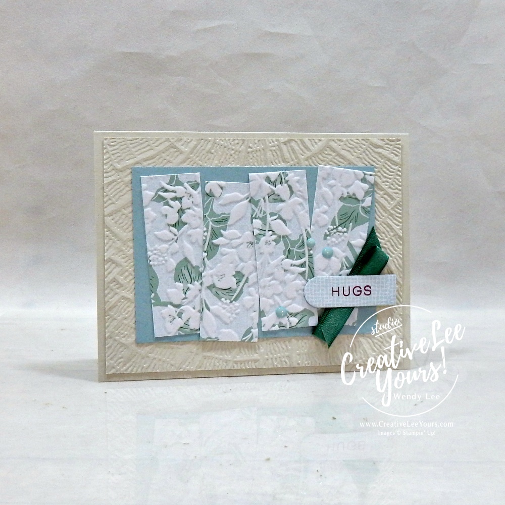 Handmade floral greeting card featuring textured embossed background, designer paper strips, satin ribbon, scalloped sentiment label, and layered embellishments.
