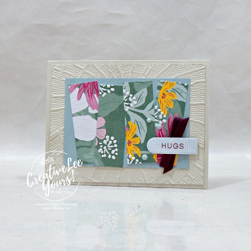 Handmade floral greeting card featuring textured embossed background, designer paper strips, satin ribbon, scalloped sentiment label, and layered embellishments.