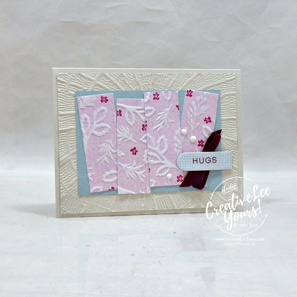 Handmade floral greeting card featuring textured embossed background, designer paper strips, satin ribbon, scalloped sentiment label, and layered embellishments.